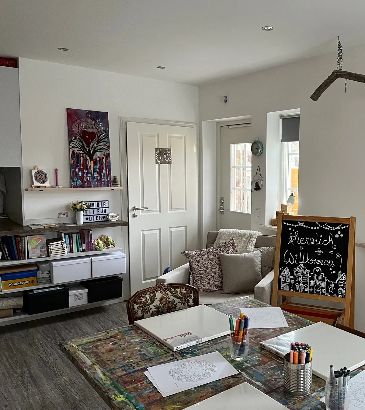 Blick ins Atelier mit Arbeitstisch, Stiften und Regal