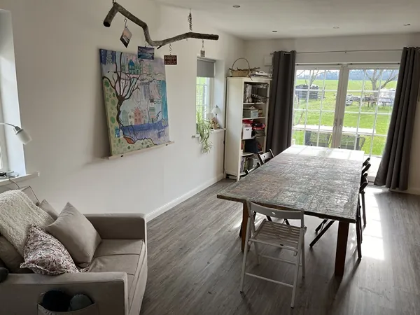 Atelierraum mit langem Holztisch, Sofa und Blick in den Garten