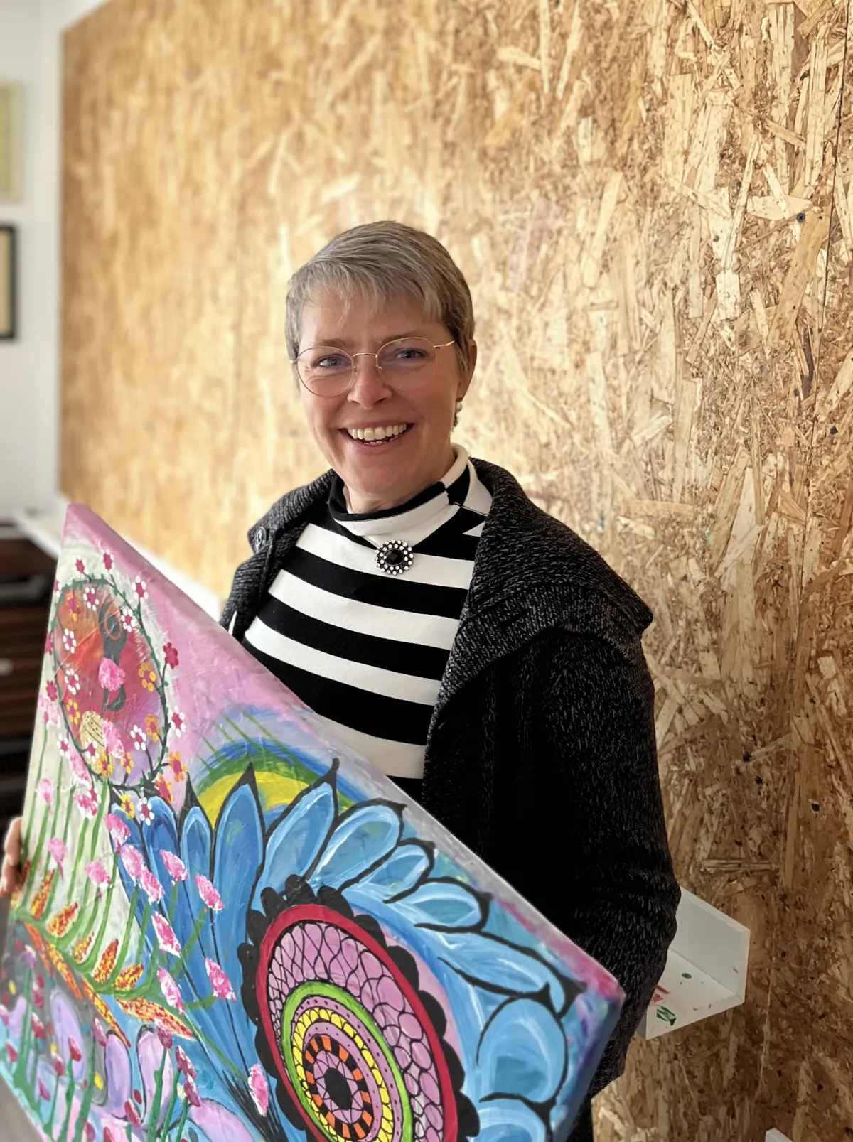 Claudia Sistek mit einem großen bunten Mandala-Bild im Atelier