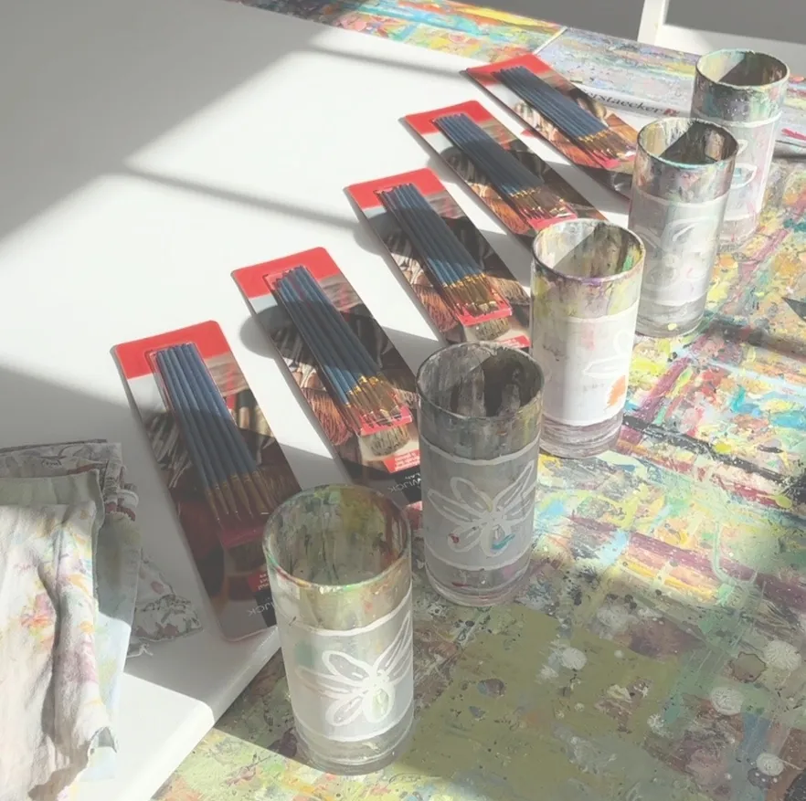 Ateliertisch mit Pinseln und Farbgläsern im Sonnenlicht