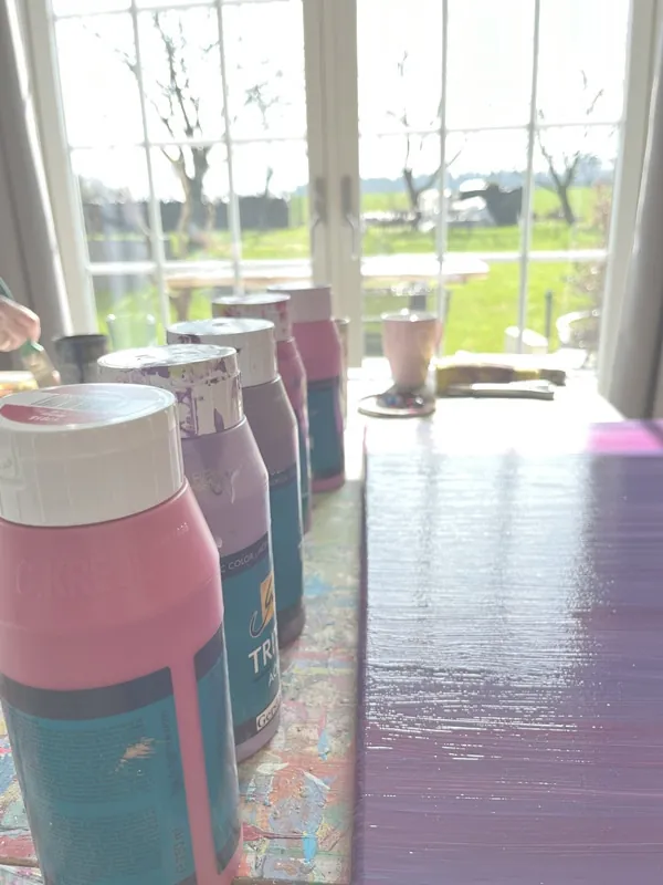 Farbflaschen auf dem Ateliertisch vor dem Fenster