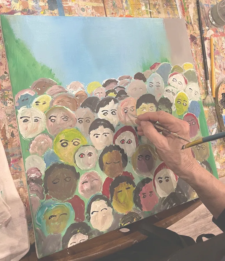 Hand malt viele bunte Gesichter auf eine Leinwand